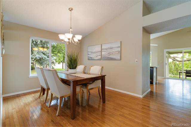 dining space featuring a chandelier, light hardwood / wood-style flooring, a wealth of natural light, and lofted ceiling