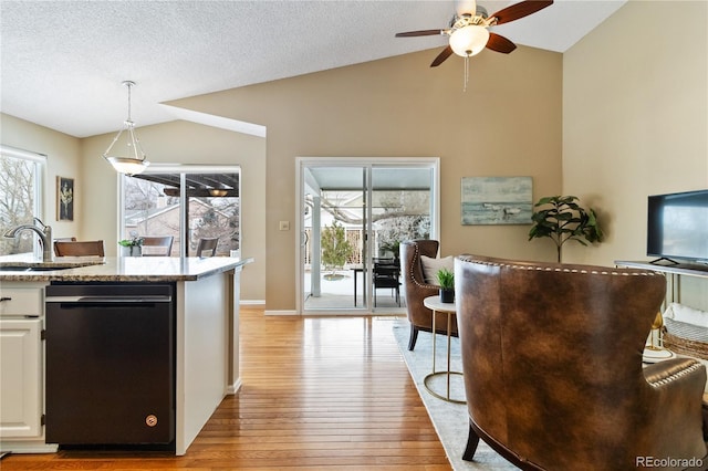 kitchen with decorative light fixtures, white cabinetry, black dishwasher, sink, and vaulted ceiling