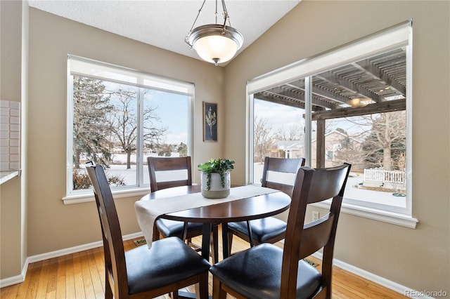 dining space with light hardwood / wood-style floors and lofted ceiling