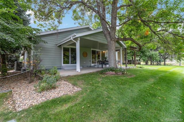 back of house with central AC, a lawn, and a patio