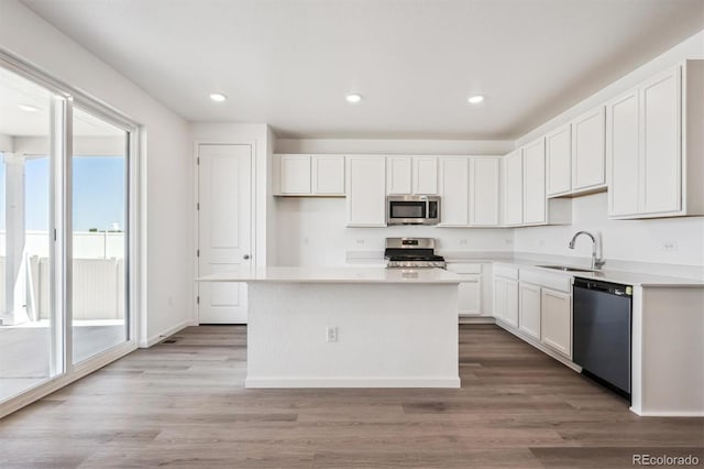 317 W Owen Ave, Keenesburg, CO 80643 - kitchen with stainless steel appliances, a sink, white cabinetry, a center island, and light wood-style flooring