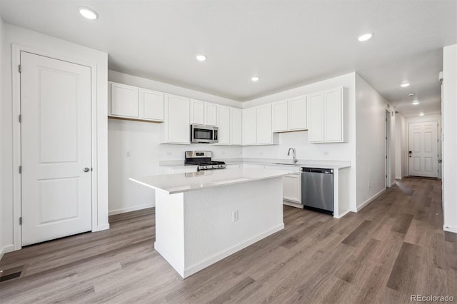 317 W Owen Ave, Keenesburg, CO 80643 - kitchen with stainless steel appliances, white cabinetry, light wood-style floors, light countertops, and a kitchen island