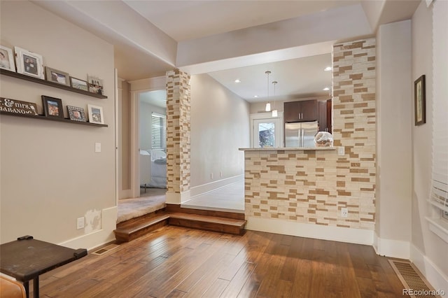 interior space featuring dark brown cabinetry, stainless steel fridge, dark hardwood / wood-style flooring, and ornate columns