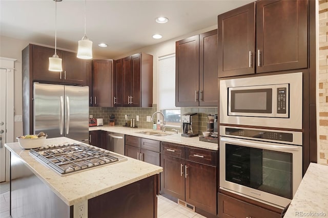 kitchen with decorative light fixtures, sink, backsplash, light stone counters, and stainless steel appliances