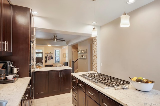 kitchen featuring decorative light fixtures, light stone countertops, stainless steel gas cooktop, and ceiling fan