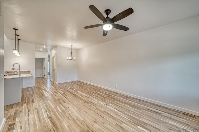 interior space featuring sink, light wood-type flooring, and ceiling fan with notable chandelier