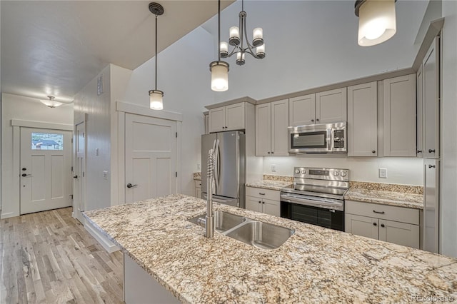 kitchen with light hardwood / wood-style flooring, light stone counters, gray cabinets, stainless steel appliances, and pendant lighting