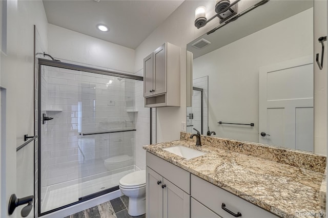 bathroom with wood-type flooring, a shower with shower door, toilet, and vanity