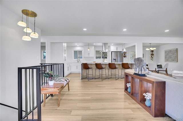 kitchen featuring hanging light fixtures, stainless steel fridge with ice dispenser, a notable chandelier, white cabinets, and light wood-type flooring