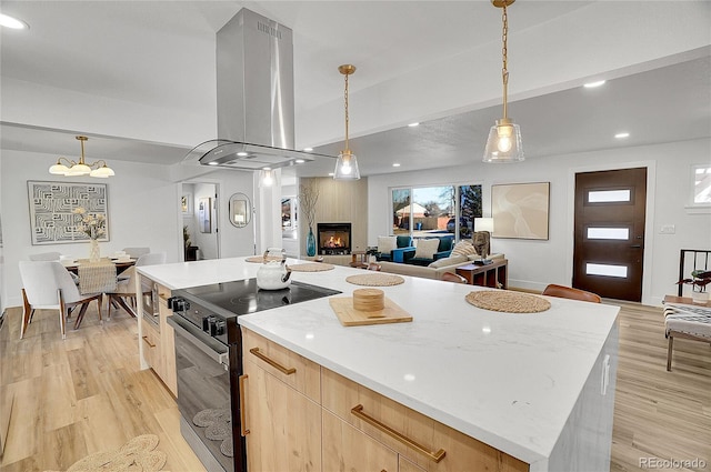 kitchen with hanging light fixtures, open floor plan, a kitchen island, island range hood, and black range with electric cooktop