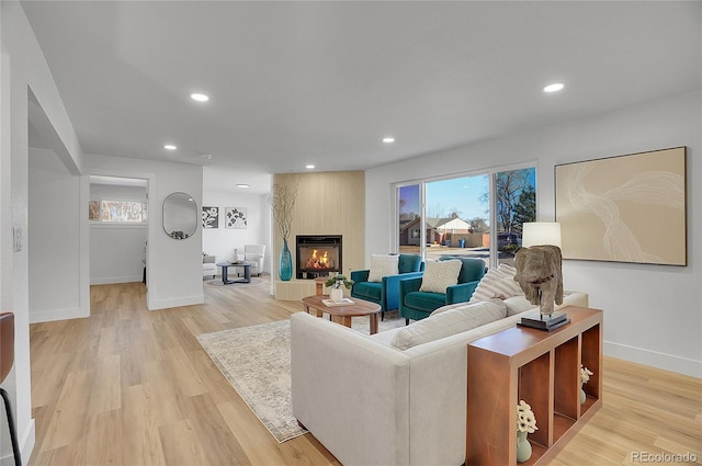 living room featuring recessed lighting, a fireplace, and light wood-style flooring