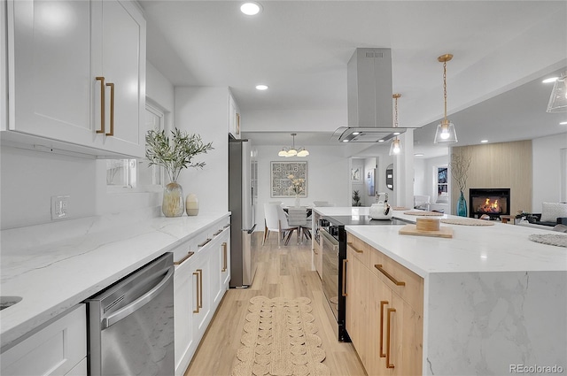 kitchen featuring island exhaust hood, white cabinetry, hanging light fixtures, and stainless steel appliances