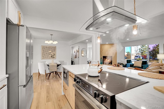 kitchen featuring stainless steel appliances, open floor plan, white cabinets, and pendant lighting