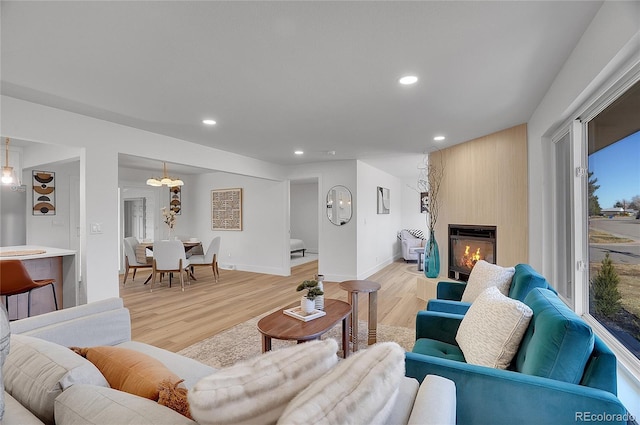 living area with a large fireplace, baseboards, light wood-style flooring, and recessed lighting