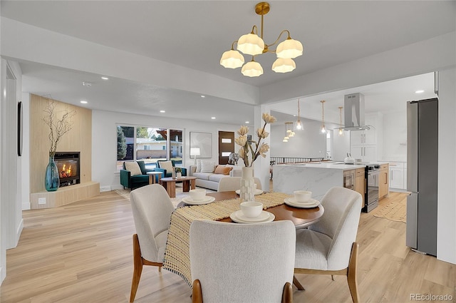 dining area with light hardwood / wood-style floors, a fireplace, and a chandelier