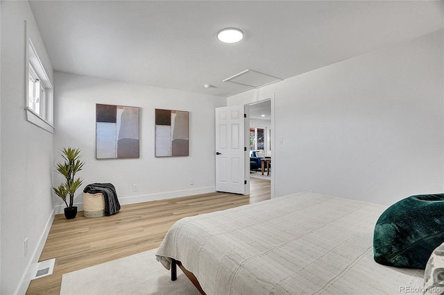 bedroom featuring baseboards, wood finished floors, visible vents, and attic access