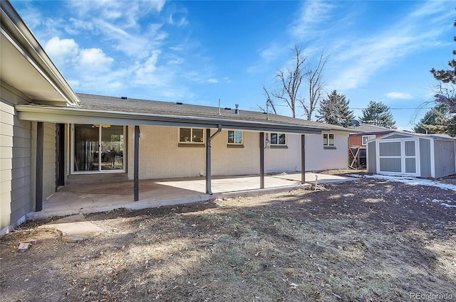 rear view of property with a patio area, an outdoor structure, brick siding, and a shed