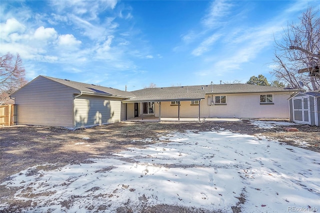 snow covered rear of property with a patio