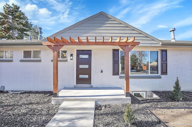 property entrance featuring a pergola and brick siding