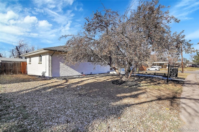 view of side of property with fence and brick siding