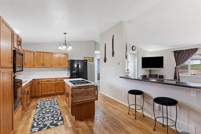 5220 Topaz Dr, Colorado Springs, CO 80918 - kitchen featuring black appliances, lofted ceiling, light wood-type flooring, decorative light fixtures, and a center island