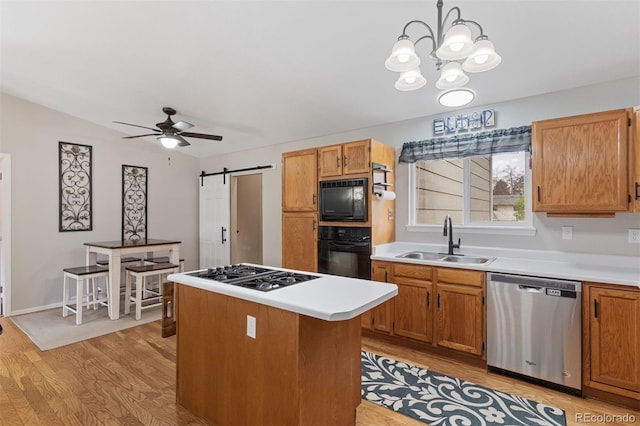 5220 Topaz Dr, Colorado Springs, CO 80918 - kitchen featuring black appliances, a sink, light wood-style flooring, a barn door, and a ceiling fan