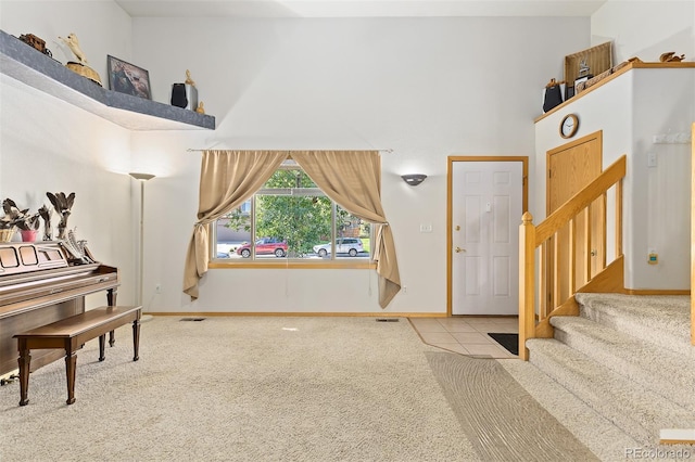 foyer entrance with a towering ceiling and light carpet