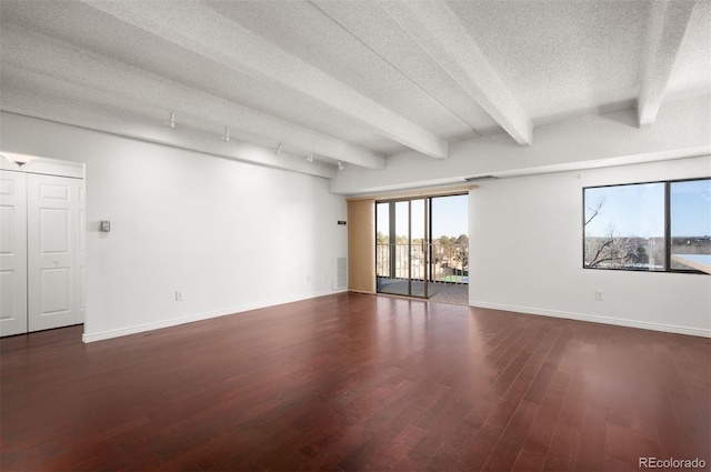 empty room with beamed ceiling, dark hardwood / wood-style floors, and a textured ceiling