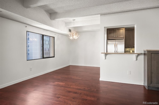 spare room featuring dark hardwood / wood-style flooring, a chandelier, and a textured ceiling