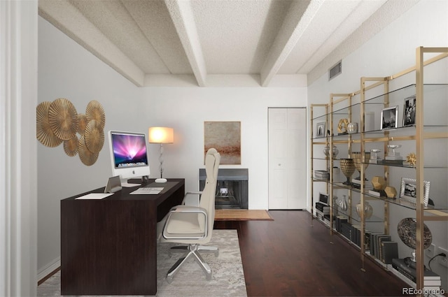 office space with beamed ceiling, hardwood / wood-style flooring, and a textured ceiling