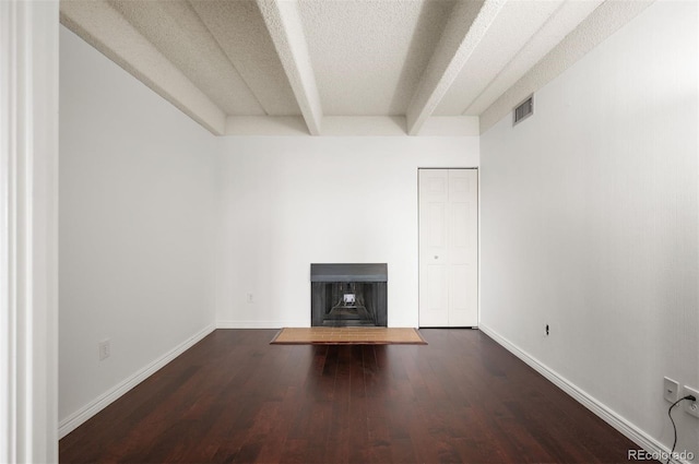 unfurnished living room featuring dark hardwood / wood-style flooring, a textured ceiling, and beam ceiling