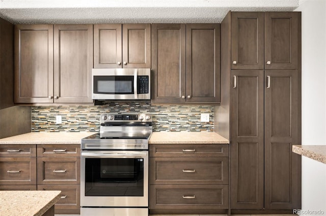 kitchen with tasteful backsplash, appliances with stainless steel finishes, and light stone countertops