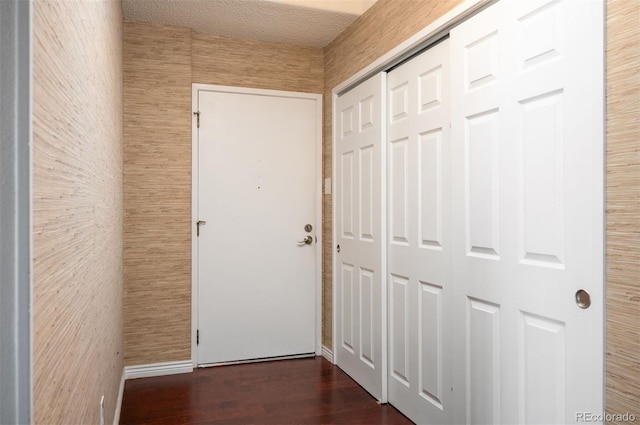 corridor with dark hardwood / wood-style flooring and a textured ceiling