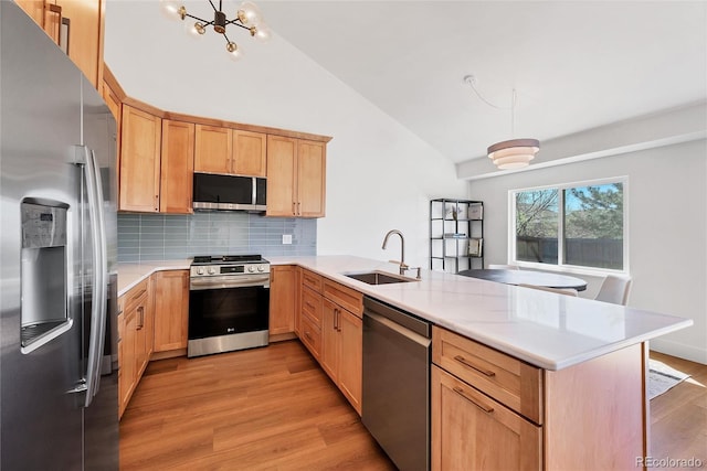 714 Sedge Way, Lafayette, CO 80026 - kitchen featuring appliances with stainless steel finishes, a sink, a peninsula, light brown cabinetry, and lofted ceiling