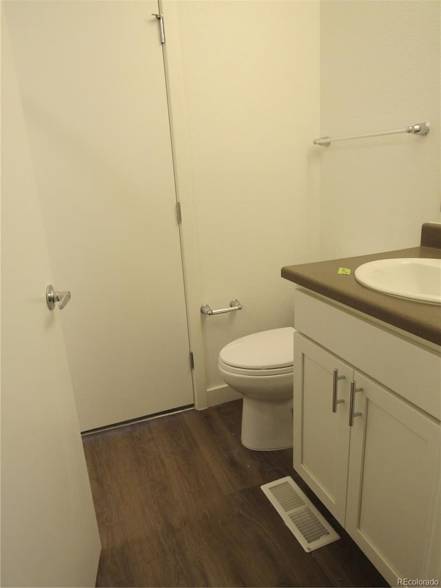 bathroom with toilet, hardwood / wood-style flooring, and vanity