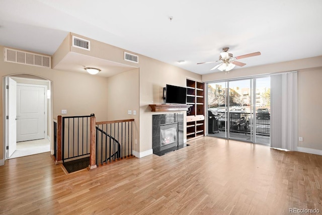 unfurnished living room featuring ceiling fan, wood-type flooring, and a fireplace