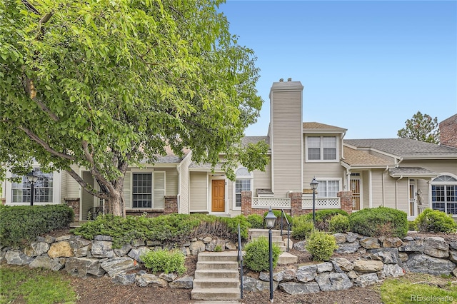 2902 W Long Cir Unit B, Littleton, CO 80120 - view of front facade with a chimney, brick siding, and a shingled roof