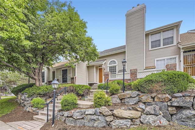 2902 W Long Cir Unit B, Littleton, CO 80120 - view of front of home featuring a chimney, stairs, and brick siding