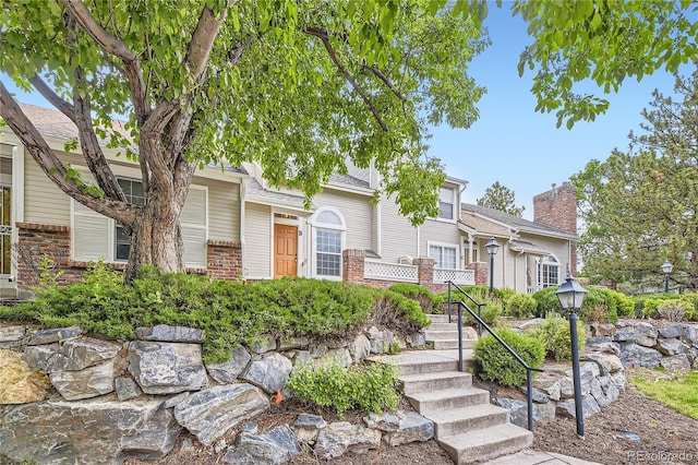 2902 W Long Cir Unit B, Littleton, CO 80120 - view of front facade with brick siding, a chimney, and stairway