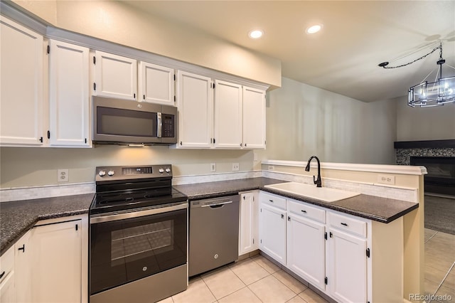2902 W Long Cir Unit B, Littleton, CO 80120 - kitchen featuring appliances with stainless steel finishes, a sink, a peninsula, light tile patterned floors, and white cabinetry