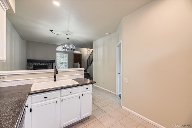 2902 W Long Cir Unit B, Littleton, CO 80120 - kitchen with a sink, white cabinets, a fireplace, a chandelier, and light tile patterned floors
