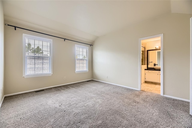 2902 W Long Cir Unit B, Littleton, CO 80120 - unfurnished bedroom featuring vaulted ceiling, light carpet, baseboards, and connected bathroom