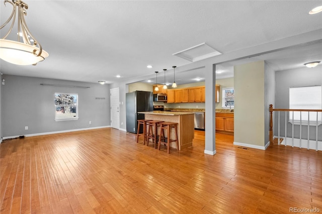 kitchen featuring a breakfast bar, light wood-type flooring, appliances with stainless steel finishes, and pendant lighting