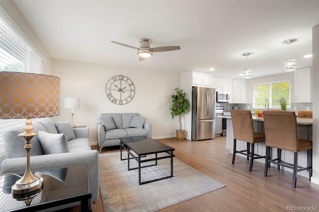 living room featuring ceiling fan and light hardwood / wood-style flooring