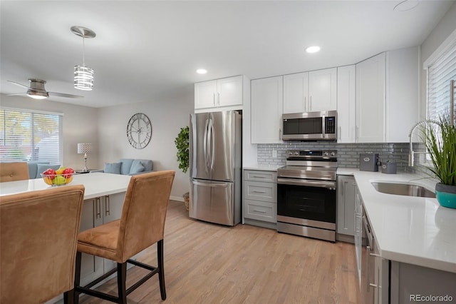 kitchen featuring hanging light fixtures, appliances with stainless steel finishes, tasteful backsplash, a kitchen bar, and white cabinetry