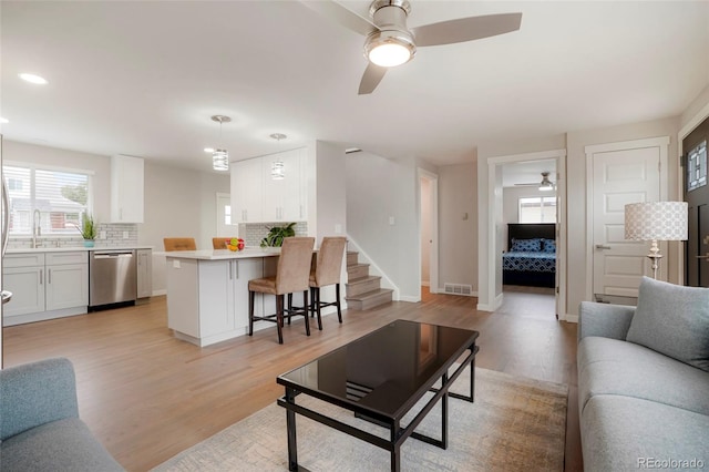 living room with light hardwood / wood-style floors, ceiling fan, and sink