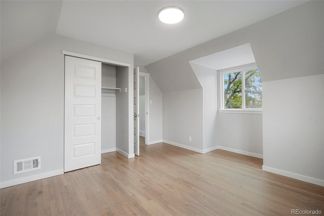 unfurnished bedroom with a closet, lofted ceiling, and light wood-type flooring