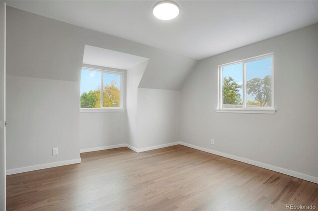 additional living space with lofted ceiling, light hardwood / wood-style flooring, and a healthy amount of sunlight