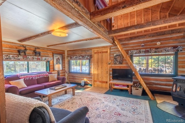 living room featuring beam ceiling, a wood stove, a wealth of natural light, and rustic walls