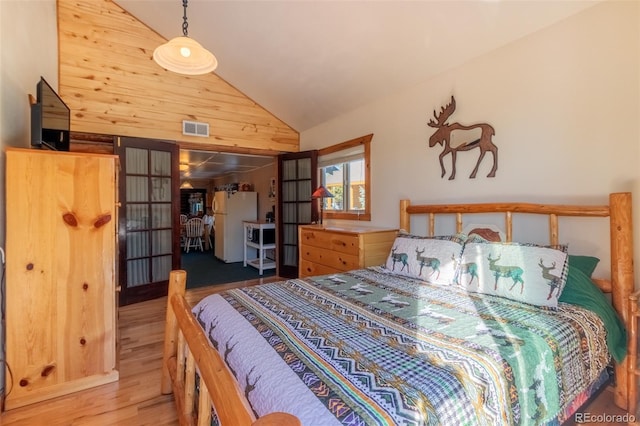 bedroom featuring wood walls, high vaulted ceiling, white refrigerator, and hardwood / wood-style flooring